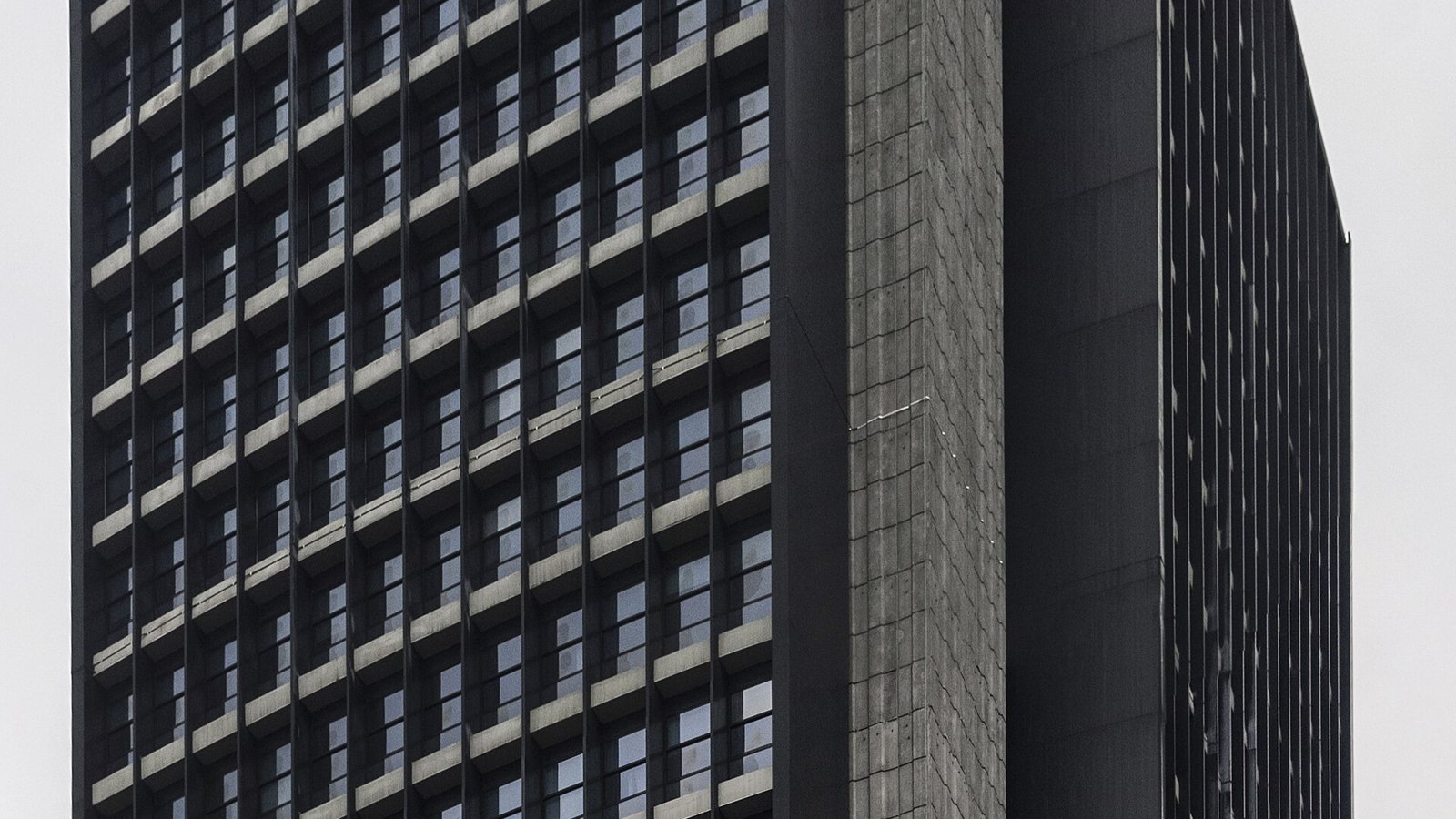 Fachada escura de prédio de concreto e vidro do Banco Central, em São Paulo, sob céu cinza