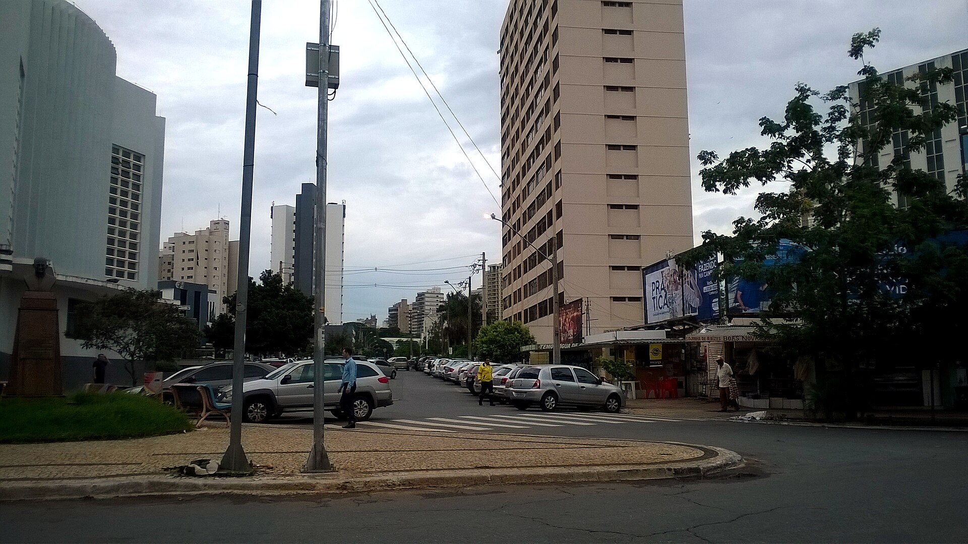 Rua no Centro de Goiânia, com prédios altos, carros estacionados e pontos de comércio de rua