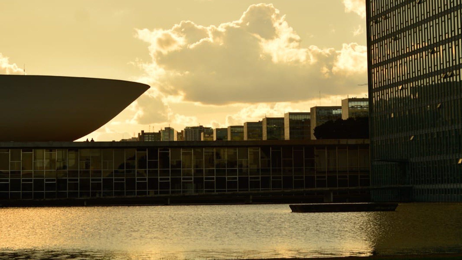 Congresso Nacional em Brasília ao entardecer, com o Senado, a Câmara e o espelho d'água em primeiro plano