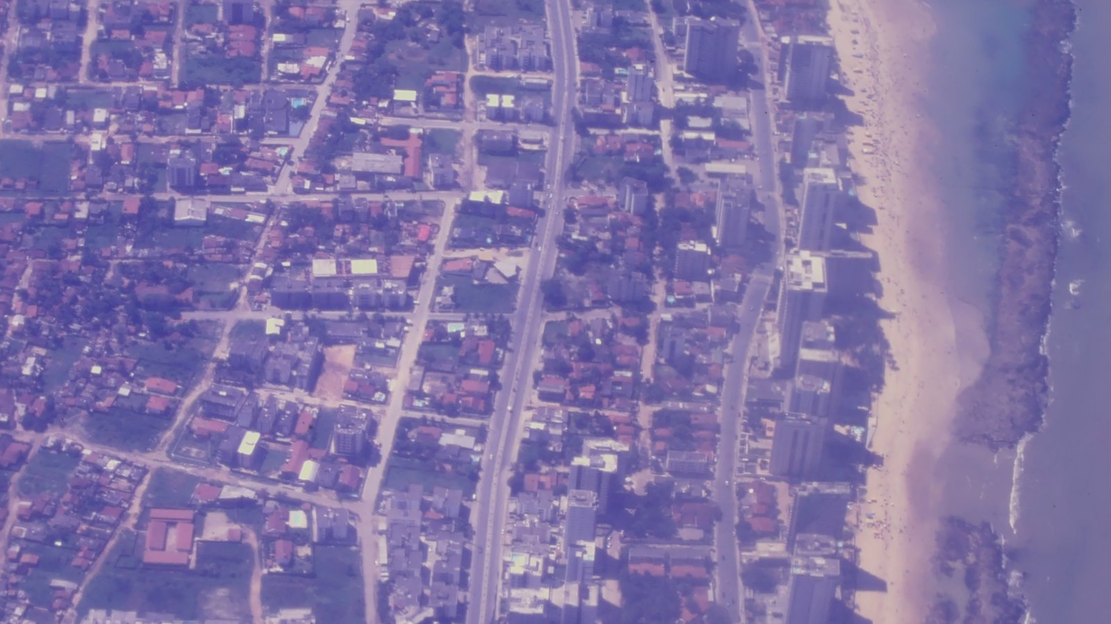Vista aérea de bairro litorâneo de Fortaleza, com quarteirões residenciais, avenida central e faixa de praia