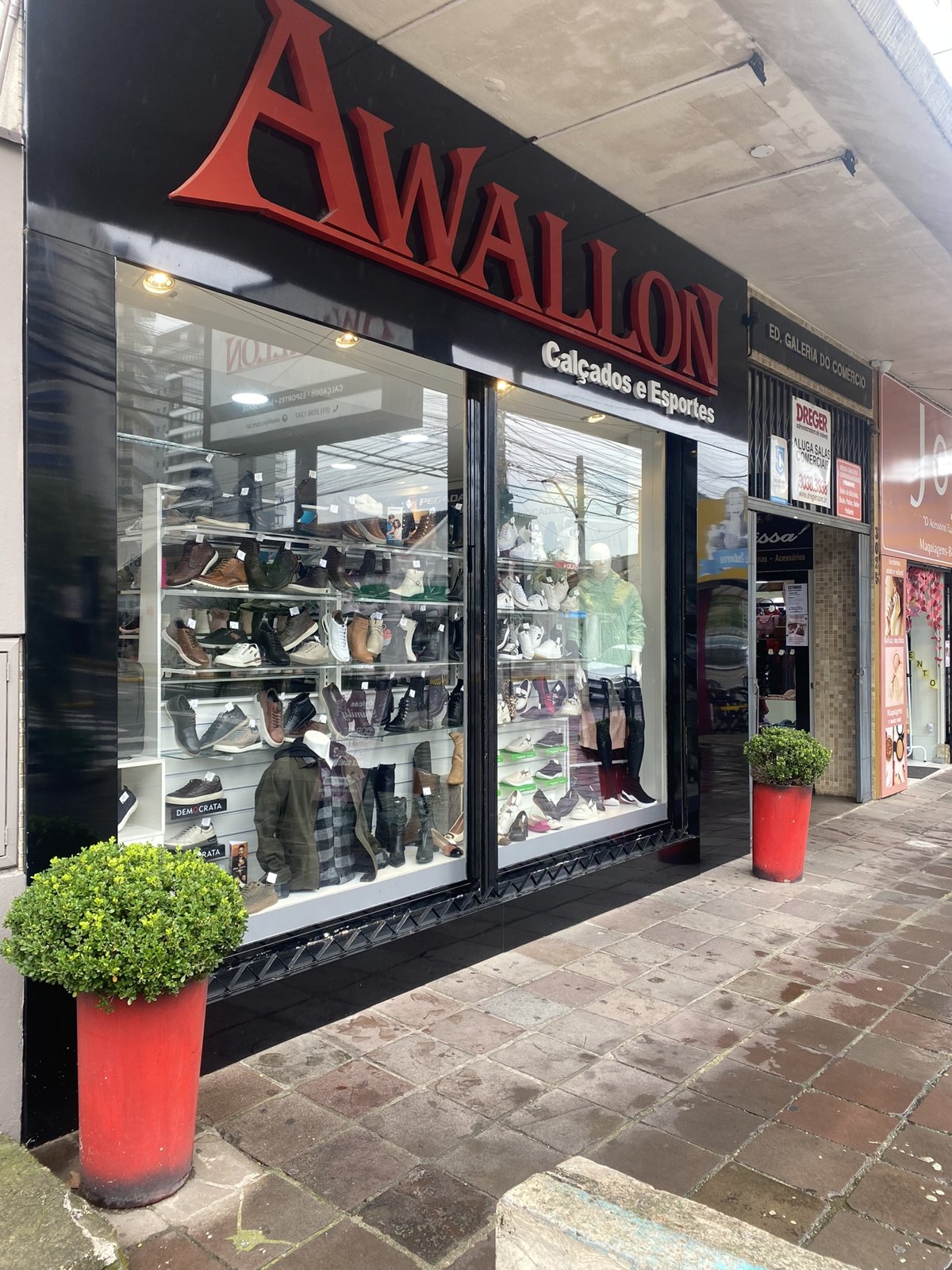 Fachada de uma loja de calçados de pequeno porte, com vitrine e produtos expostos